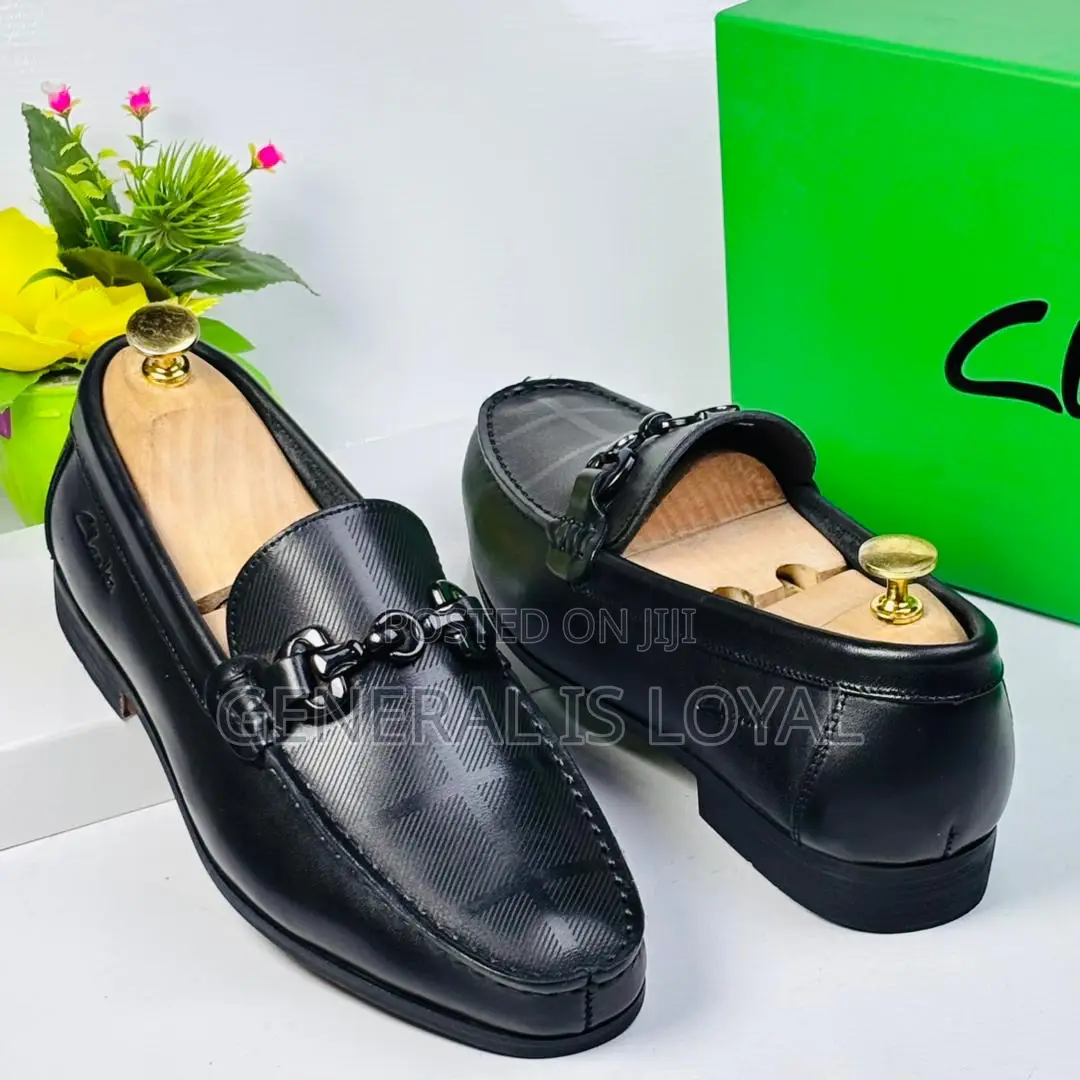 Black Clarks Loafers With A Metal Buckle And Patterned Leather