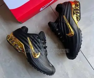 A Black Nike Sneaker With a Glossy Upper and a Metallic Gold Swoosh